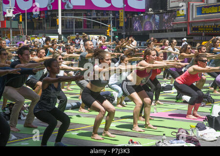 Yoga Enthusiasten nehmen kostenlose Kurse in den jährlichen Times Square Sommersonnenwende Feier mit Klassen den ganzen Tag inmitten der Material glitz der Nachbarschaft, New York City. Stockfoto