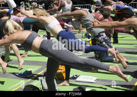 Yoga Enthusiasten nehmen kostenlose Kurse in den jährlichen Times Square Sommersonnenwende Feier mit Klassen den ganzen Tag inmitten der Material glitz der Nachbarschaft, New York City. Stockfoto