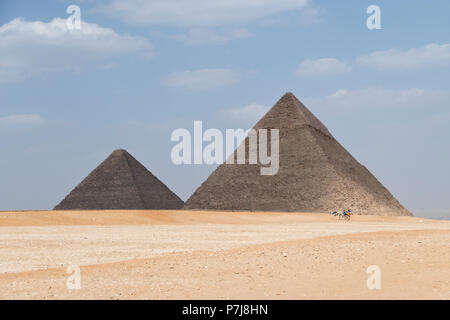 Pferdewagen, führen Touristen um die Große Pyramide von Gizeh (links) und die Pyramide von khafre (rechts) bei Gizeh, Ägypten. Stockfoto