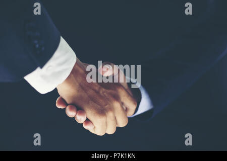 Business Partnerschaft treffen Konzept und Business Handshake für erfolgreiche Investitionen vorrangig auf schwarzem Hintergrund Stockfoto