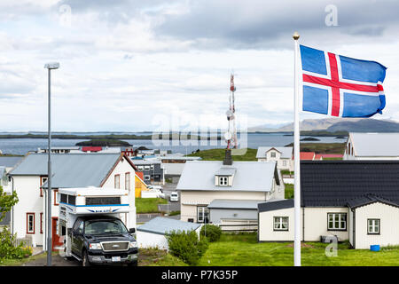 Stykkisholmur, Island - Juni 17, 2018: Nationale land Flagge mit blauen, roten Streifen im Wind auf bewölkt bewölkten Tag, stadtbild Skyline von kleinen Fishin Stockfoto