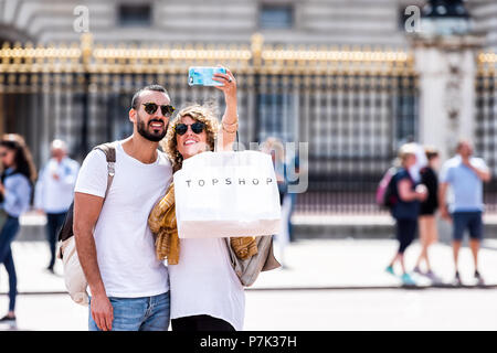 London, UK, 21. Juni 2018: Romantische junge Glücklich lächelnde Paar ständige Einnahme von selfie vor Gold, golden Buckingham Palace closeup Zaun, topsh Stockfoto