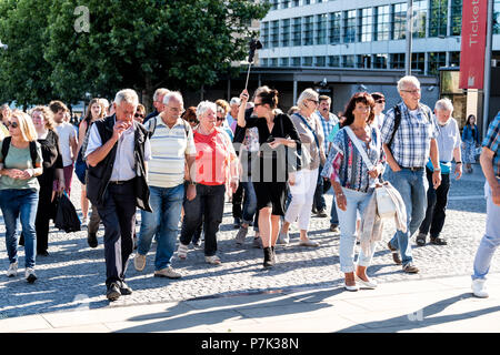 London, Großbritannien, 22. Juni 2018: die Masse von viele Fußgänger auf dem Bürgersteig Straße Straße durch die Tower Bridge Pier, sightseeing tour guide Frau carryi Stockfoto