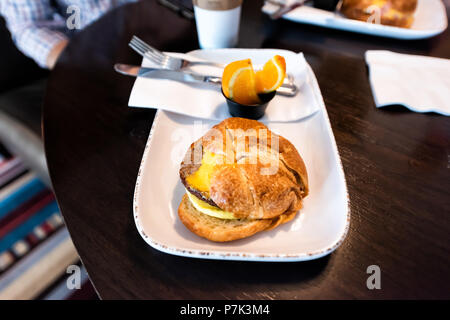 Nahaufnahme von herzhaften Frühstück croissant Sandwich gelb Dessert in Bäckerei, Shop, Cafe, speichern Tabelle auf Platte mit Wurst, Käse, Orangenscheiben f Stockfoto