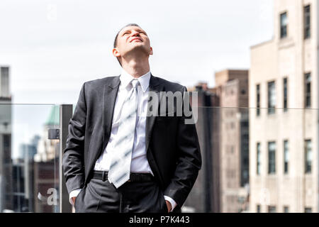Junge Geschäftsmann im Anzug auf der Suche oben am Himmel in New York City Skyline Skyline in Midtown Manhattan nach Interview Pause an skyscra Stockfoto