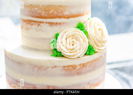 Makro Nahaufnahme von drei tiered Vanille goldenen Licht weiß gelb Creme schwamm Hochzeitstorte mit rose Blumen Dekoration auf helle, künstliche Col Stockfoto