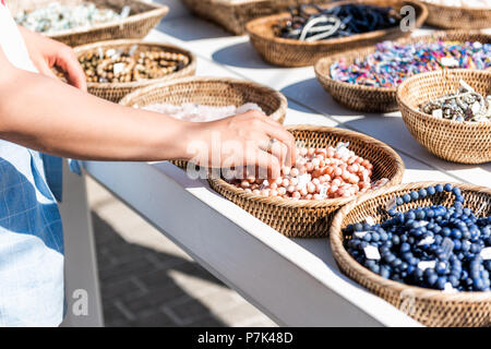 Nahaufnahme der jungen Frau Einkaufen für bunten Stein Strand Armbänder Hand berühren im freien Markt shop shop in Europäischen, Griechenland, Italien, Mediterranea Stockfoto