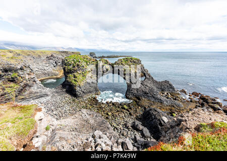 Landschaft Blick auf berühmte Gatklettur Arch Rock in der Nähe von Hellnar, National park Snaefellsnes Halbinsel, Island mit felsigen ozean meer wellen, grünes Gras, Moos Stockfoto