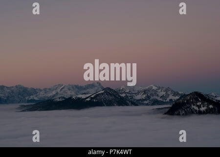 Blick auf den Jochberg im Winter über den Wolken in Richtung des Wettersteingebirges, Bayerische Alpen, Oberbayern, Bayern, Deutschland Stockfoto