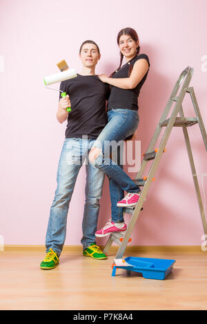 Foto der jungen Frau und Mann mit paint Roller steht in der Nähe der Treppe Stockfoto