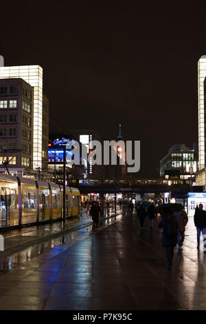 Eine Straßenbahn am Alexanderplatz in der Nacht im Regen mit Kaufhäusern und dem Roten Rathaus im Hintergrund in Berlin, Stockfoto