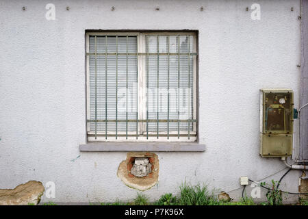 Vergitterten Fenster von einem verfallenen Gebäude mit einem alten Strom Verteiler, Stockfoto