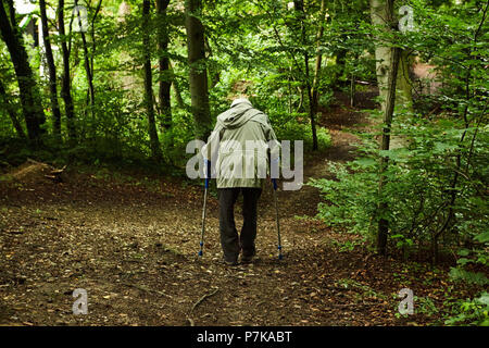 Alte Mann Frau 70-90 Jahre mit Krücken laufen im Wald Stockfoto