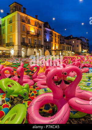 Panorama auf der Piazza Grande in Locarno am Abend mit Kunst Installation von bunten Kunststoff Flamingos und andere Gummi Tiere Stockfoto