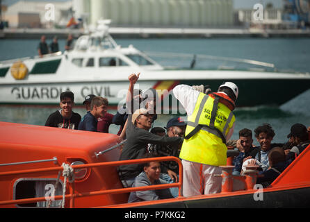 Malaga, Spanien. 7. Juli 2018. Ein Migrant, der von einem Beiboot im Mittelmeer gerettet wurde, Wellen vor seiner Ankunft am Hafen von Malaga. Mitglieder der Spanischen Sicherheit auf See gerettet 24 Migranten an Bord ein Beiboot in der Nähe der Küste von Malaga und brachte am Hafen von Malaga, wo sie durch das Spanische Rote Kreuz unterstützt wurden. Credit: SOPA Images Limited/Alamy leben Nachrichten Stockfoto