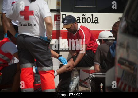 Malaga, Spanien. 7. Juli 2018. Ein Migrant, der von einem Beiboot im Mittelmeer gerettet wurde, wird von den Mitgliedern des spanischen Roten Kreuzes unterstützt nach seiner Ankunft am Hafen von Malaga. Mitglieder der Spanischen Sicherheit auf See gerettet 24 Migranten an Bord ein Beiboot in der Nähe der Küste von Malaga und brachte am Hafen von Malaga, wo sie durch das Spanische Rote Kreuz unterstützt wurden. Credit: SOPA Images Limited/Alamy leben Nachrichten Stockfoto