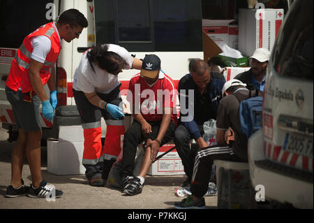 Malaga, Spanien. 7. Juli 2018. Ein Migrant, der von einem Beiboot im Mittelmeer gerettet wurde, wird von den Mitgliedern des spanischen Roten Kreuzes unterstützt nach seiner Ankunft am Hafen von Malaga. Mitglieder der Spanischen Sicherheit auf See gerettet 24 Migranten an Bord ein Beiboot in der Nähe der Küste von Malaga und brachte am Hafen von Malaga, wo sie durch das Spanische Rote Kreuz unterstützt wurden. Credit: SOPA Images Limited/Alamy leben Nachrichten Stockfoto