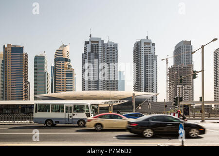 Autos auf der Straße vor dem futuristischen Bau der Dubai Metro Station und moderne Wolkenkratzer in Dubai, Vereinigte Arabische Emirate