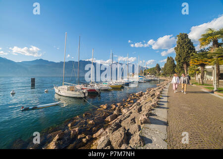 Touristen zu Fuß entlang der Seepromenade von Malcesine am Ostufer des Gardasees, in der Provinz Verona, Venetien, Italien. Stockfoto