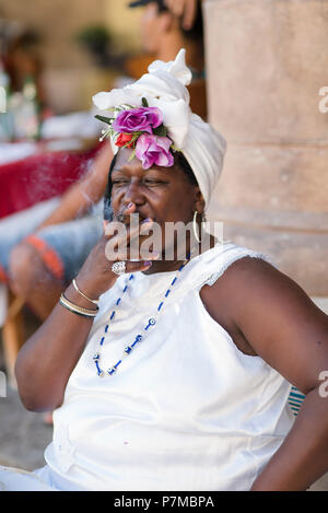 Theresa die Wahrsagerin eine kubanische Zigarre rauchen und genießen das schöne Wetter auf der Plaza de la Catedral, Havanna, Kuba. Stockfoto