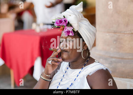 Theresa die Wahrsagerin eine kubanische Zigarre rauchen und genießen das schöne Wetter auf der Plaza de la Catedral, Havanna, Kuba. Stockfoto