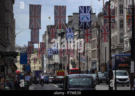 Blick auf den Strand in London, UK Richtung Trafalgar Square, viele Fahnen auf Kabel über die Straße hoch über Fußgänger und Verkehr aufgehängt. Stockfoto