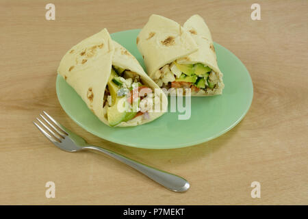 Chicken Salat Wraps mit Avocado, Gurke, Tomate und Feta in Tortilla auf der grünen Platte Stockfoto