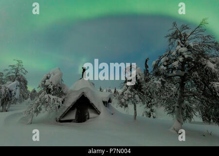 Northern Lights auf Holz Hütte mit Schnee bedeckt, Pallas-Yllastunturi Nationalpark, Muonio, Lappland, Finnland Stockfoto