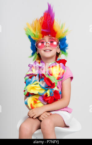 Lustig schöne Party kleines Mädchen in der Verkleidung mit Perücke in vielen Farben und Rosa runde Sonnenbrille Stockfoto