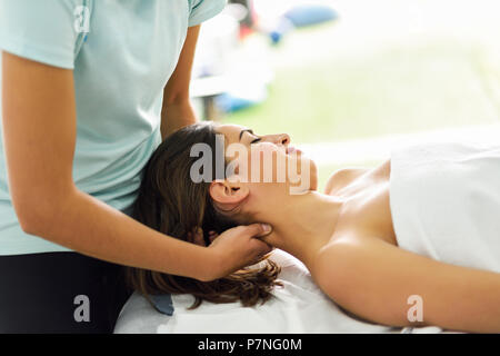 Junge kaukasier lächelnde Frau mit einem Kopf Massage im Spa Center mit geschlossenen Augen. Weibliche Patienten ist, die Behandlung von professionellen therapi Stockfoto