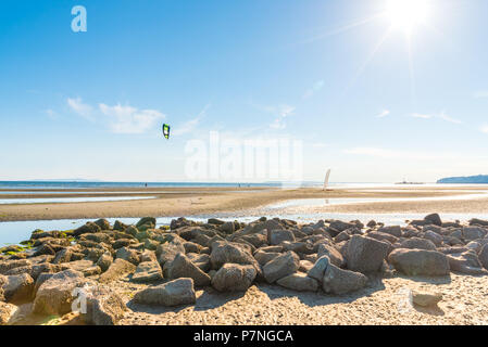 Barnacle fallenden Felsen im Vordergrund, Tide Pools und Strand bei Ebbe, Pazifischer Ozean, und Kitesurfen Segeln in der Entfernung auf einer sonnigen Sommer Abend Stockfoto