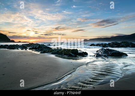 Das ist ein Bild von einem Stream auf einem Strand in Donegal Irland bei Sonnenuntergang. Klippen kann in der Ferne zu sehen ist. Stockfoto