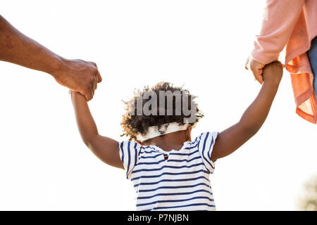 Kleines Mädchen Hand in Hand mit ihren Eltern. Stockfoto