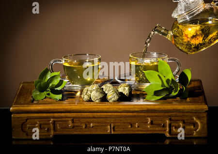 horizontale Foto Glas Teekanne Fluss grüner Tee in Tasse auf braunem Hintergrund, Tee-Zeremonie Stockfoto