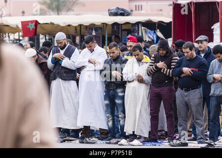 Musulmanes orando Frente a una Mezquita, Plaza Jamaa el Fna, Marrakech, Marruecos, Norte de Afrika, continente Africano. Stockfoto