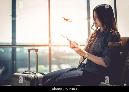 Beauty asiatische Frau mit Koffer Gepäck warten auf Abfahrt während der Verwendung von Smart Phone in der Airport Lounge. Weibliche Reisende und touristische Themen. Hoher See Stockfoto