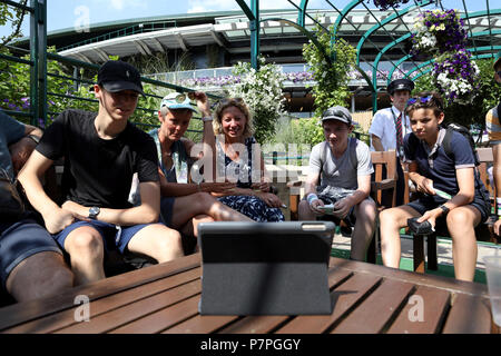 Tennis Fans sehen das England Fußball WM-Viertelfinale gegen Schweden auf eine Tablette am Tag sechs der Wimbledon Championships in der All England Lawn Tennis und Croquet Club, Wimbledon. Stockfoto