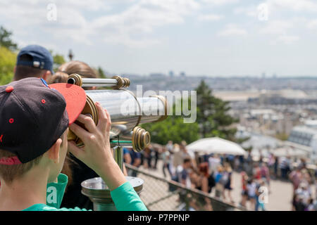 Jungen auf der Suche durch ein Teleskop auf der Pariser Skyline der Stadt. Stockfoto