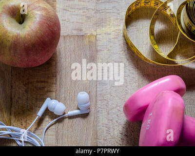 Stillleben mit rosa Gewichte und gelbe Bandmaß und einen Apfel von oben Sicht. Fitness. sport.Konzept. Stockfoto