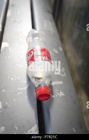Leere Coca-Cola-Plastikflasche in einem Busunterstand in Dumfries, Schottland. Stockfoto
