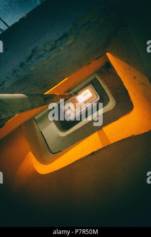 Orange leuchtet ein furchtsames Beton Treppen in einem zerstörten Gebäude. Stockfoto