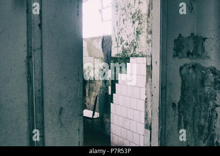 Abgenutzte bad Wände mit gerissenen weißen Fliesen. Stockfoto