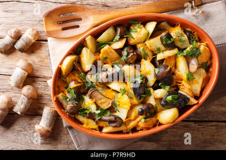 Bratkartoffeln mit Steinpilzen, Cheddar Käse und Kräutern close-up in einer Schüssel auf einem Tisch. horizontal oben Ansicht von oben Stockfoto