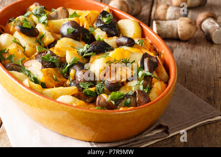 Hausgemachte Speisen: Pilze mit Kartoffeln, Dill, Petersilie und Cheddar Käse in einer Auflaufform close-up auf dem Tisch. Horizontale Stockfoto