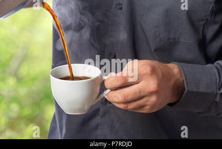 Man gießt frischer, heißer Kaffee aus der Kaffeemaschine in die Schale Stockfoto