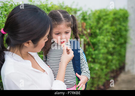 Mutter ihre Tochter Fütterung mit Snack, bevor sie zur Schule gehen. Zurück zu Schule und Bildung Konzept. Home sweet home und glückliche Familie Thema. Stockfoto