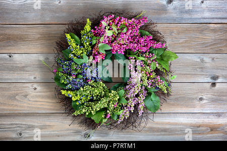 Bunte künstlichen Kranz aus Blumen und Blätter auf vintage Holz Hintergrund Stockfoto