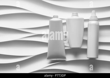Schönen format Poster mit glatten grauen Wellen abstrakt Hintergrund mit grau-Tonarten, mit sauberen weißen Kunststoffbehälter: Flaschen, Creme jar Stockfoto