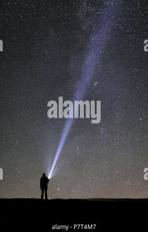 Silhouette einer Tourist mit einer Taschenlampe beobachten, schönen, weiten blauen Nachthimmel mit Sternen und Galaxien Stockfoto