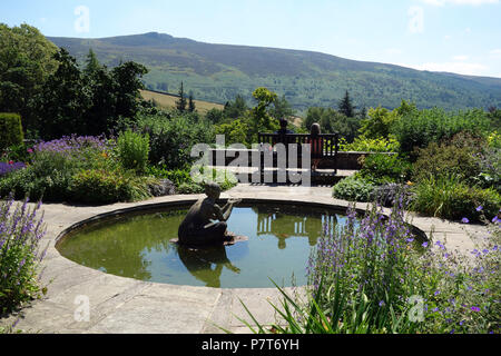 Ein Paar sitzt auf einer Holzbank an der Simon von Seat im Parcevall Hall Gardens, Skyreholme, Appletreewick, Wharfedale, Yorkshire, England, UK. Stockfoto